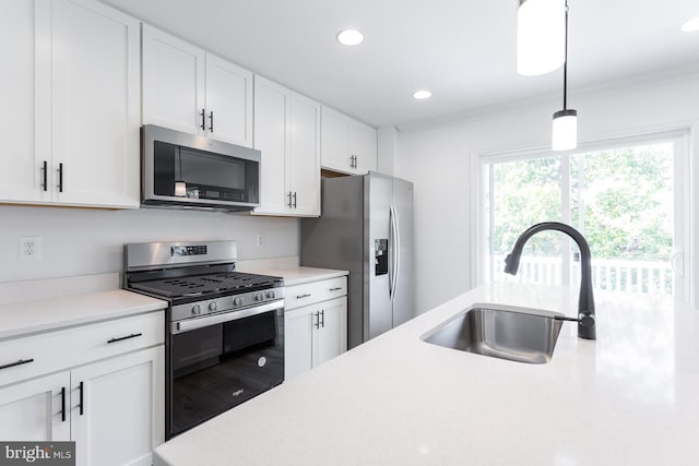 kitchen featuring sink, hanging light fixtures, crown molding, white cabinets, and appliances with stainless steel finishes