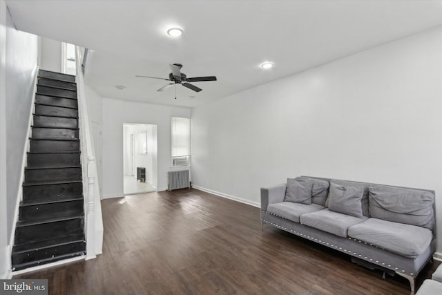 living room featuring dark hardwood / wood-style floors, ceiling fan, and radiator heating unit