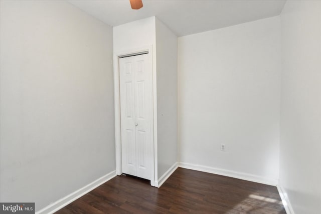 unfurnished bedroom with dark hardwood / wood-style flooring, a closet, and ceiling fan