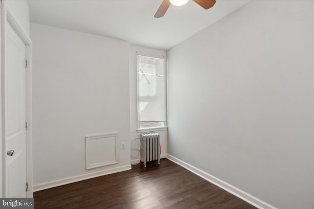 spare room with radiator heating unit, ceiling fan, and dark wood-type flooring