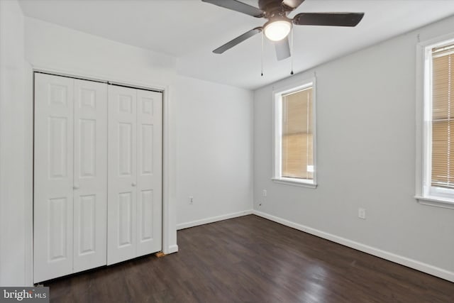 unfurnished bedroom featuring dark hardwood / wood-style flooring, multiple windows, and ceiling fan