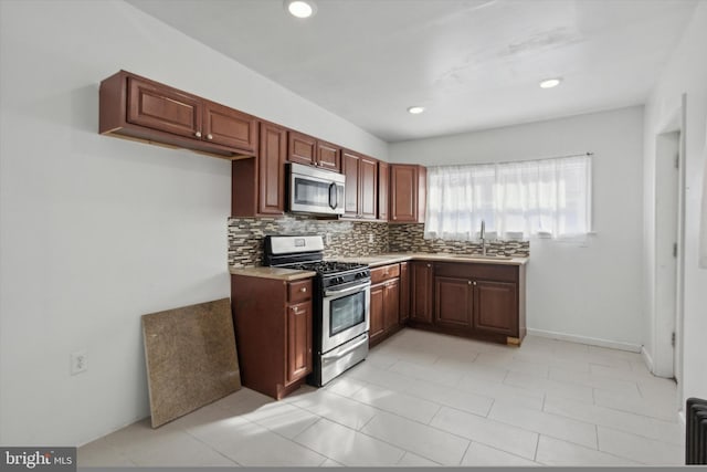 kitchen with tasteful backsplash, sink, light tile patterned floors, and stainless steel appliances