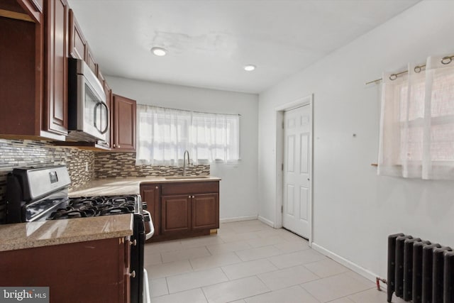 kitchen with range, sink, decorative backsplash, light stone countertops, and radiator heating unit