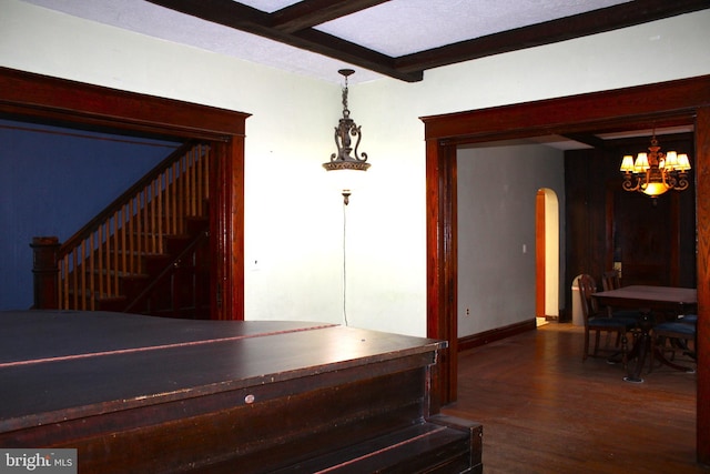 hallway with beamed ceiling, dark hardwood / wood-style floors, and a notable chandelier