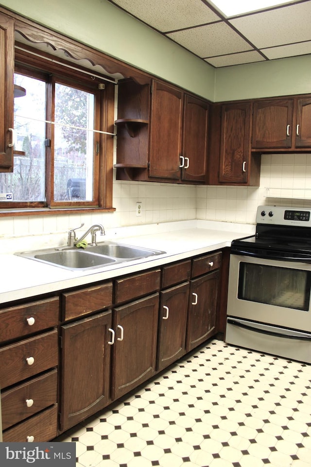 kitchen featuring dark brown cabinetry, sink, stainless steel range with electric cooktop, and a drop ceiling