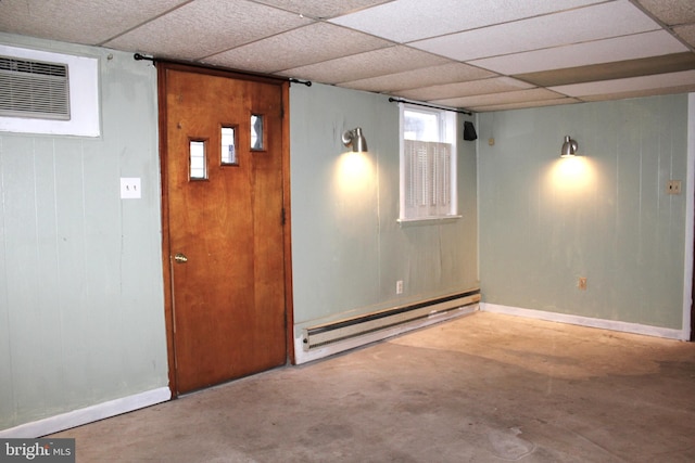 basement featuring a wall unit AC, a paneled ceiling, wooden walls, and a baseboard radiator