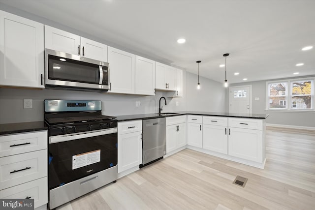 kitchen with stainless steel appliances, white cabinetry, and hanging light fixtures