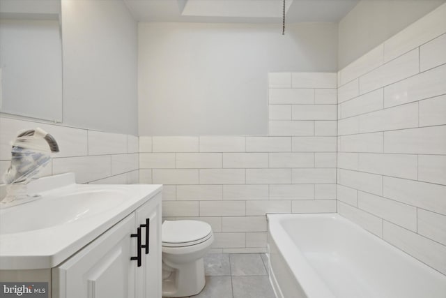 bathroom with a washtub, tile patterned flooring, toilet, vanity, and tile walls