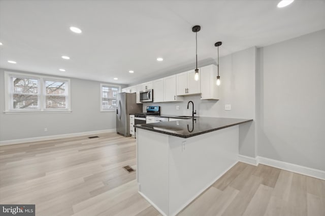 kitchen with pendant lighting, white cabinets, sink, appliances with stainless steel finishes, and kitchen peninsula