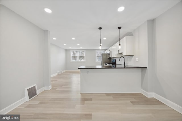 kitchen with white cabinets, pendant lighting, kitchen peninsula, and light hardwood / wood-style floors