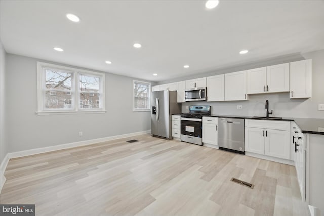 kitchen with white cabinets, light hardwood / wood-style floors, sink, and appliances with stainless steel finishes