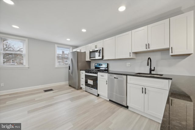 kitchen featuring white cabinets, stainless steel appliances, light hardwood / wood-style floors, and sink