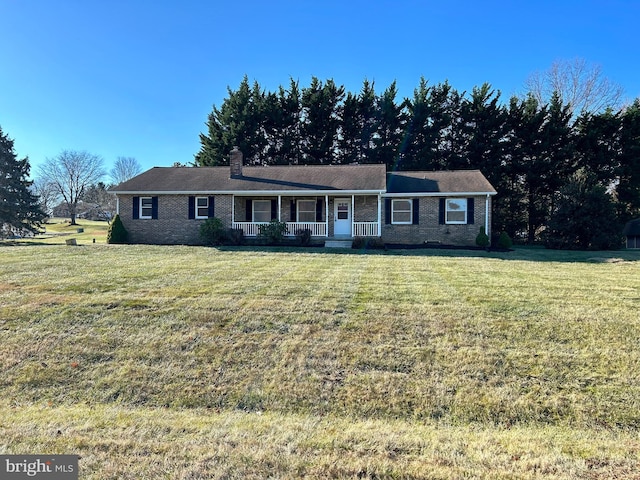 ranch-style home featuring covered porch and a front yard