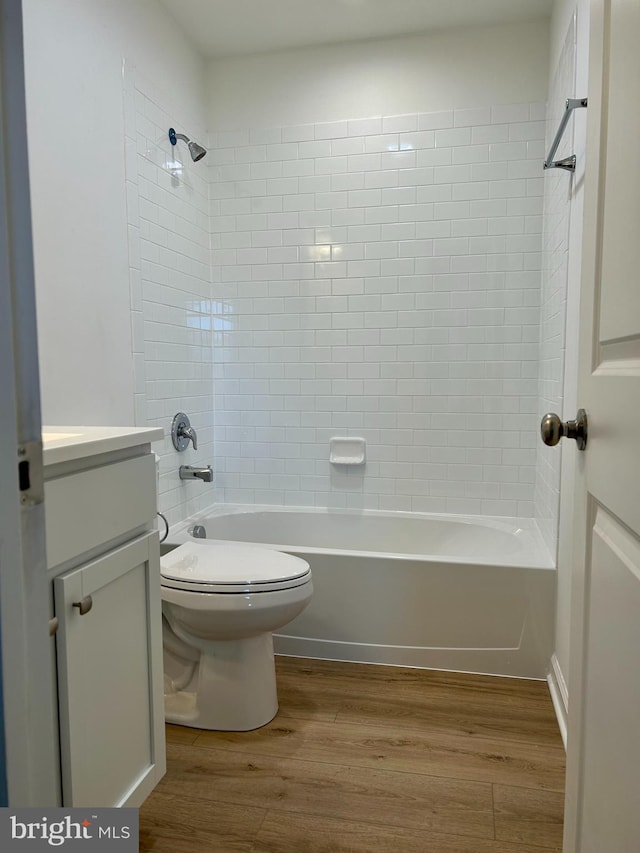 full bathroom with hardwood / wood-style flooring, vanity, toilet, and tiled shower / bath