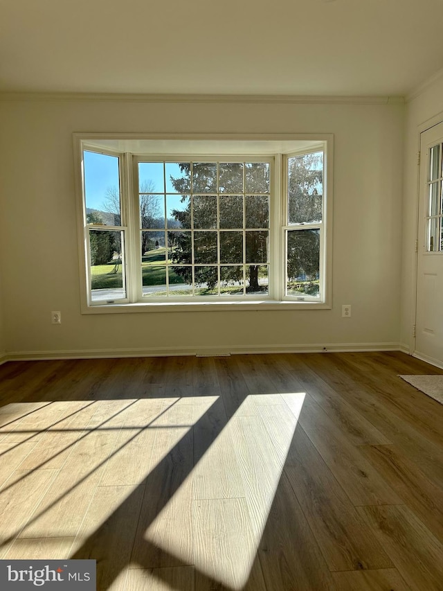 empty room with dark hardwood / wood-style floors and crown molding