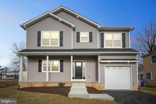 traditional-style home with a garage, driveway, and fence