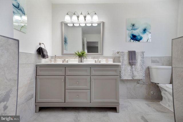 bathroom featuring vanity, tile walls, and toilet