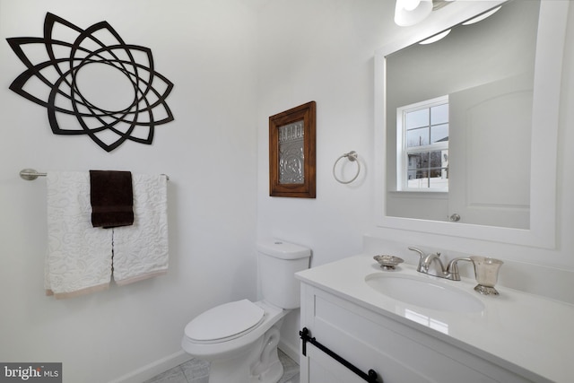 half bath featuring toilet, vanity, and baseboards