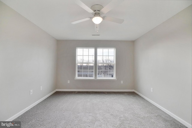 spare room with carpet floors, visible vents, baseboards, and a ceiling fan