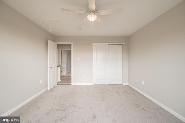 unfurnished bedroom with attic access, baseboards, ceiling fan, carpet, and a closet