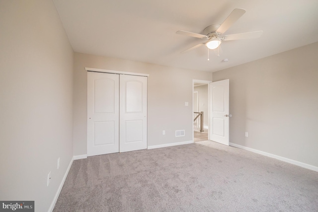 unfurnished bedroom featuring carpet floors, a closet, and ceiling fan