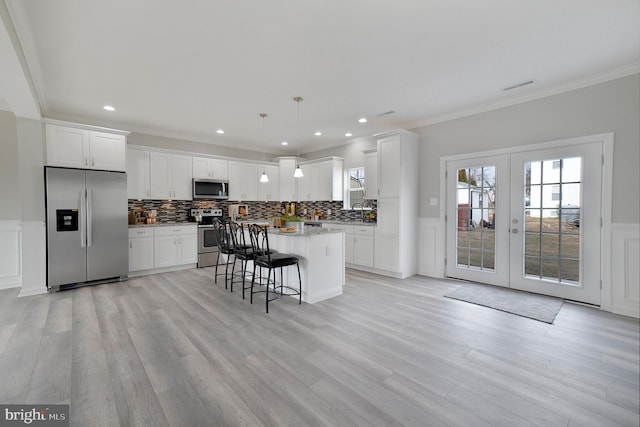 kitchen featuring a breakfast bar area, a kitchen island, visible vents, french doors, and appliances with stainless steel finishes