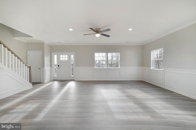 foyer with light hardwood / wood-style floors, ceiling fan, a healthy amount of sunlight, and ornamental molding