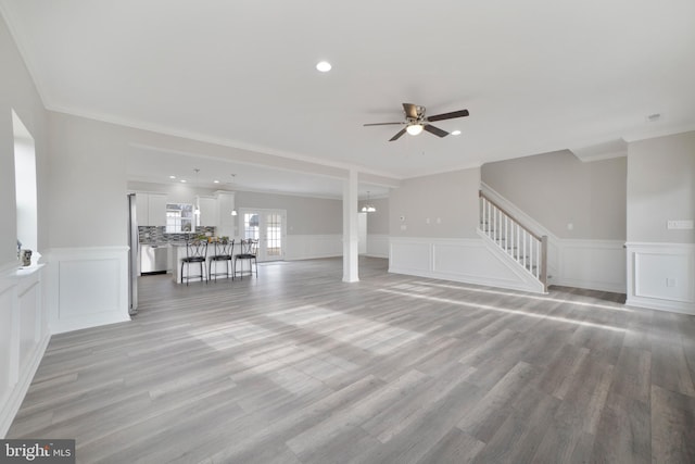 unfurnished living room with ceiling fan, light wood-type flooring, and ornamental molding