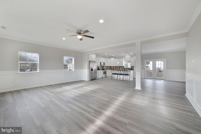 unfurnished living room featuring recessed lighting, a ceiling fan, light wood-style floors, ornamental molding, and french doors