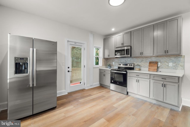 kitchen featuring gray cabinets, decorative backsplash, light hardwood / wood-style flooring, and stainless steel appliances