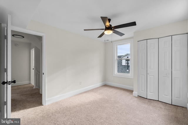 unfurnished bedroom with a closet, light colored carpet, and ceiling fan