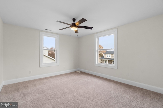 carpeted empty room with ceiling fan and a healthy amount of sunlight