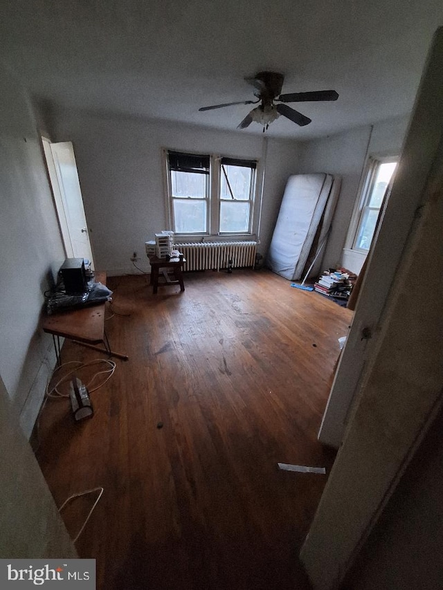 interior space with hardwood / wood-style floors, radiator heating unit, and ceiling fan