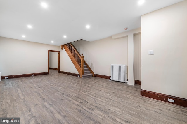 basement with radiator heating unit and light hardwood / wood-style flooring