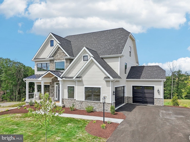 craftsman-style house featuring a front lawn, covered porch, and a garage