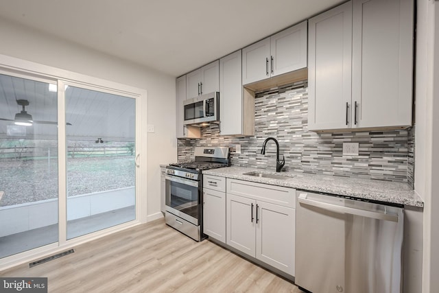 415 Tamara Cir, Newark, DE 19711 - kitchen with stainless steel appliances, a sink, light wood-style floors, decorative backsplash, and light stone countertops