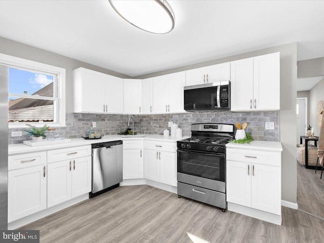 kitchen with white cabinets, appliances with stainless steel finishes, and light wood-type flooring