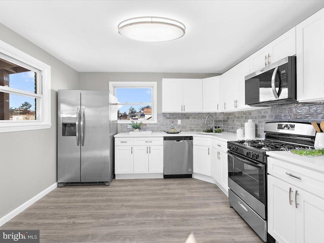 kitchen featuring stainless steel appliances, white cabinetry, plenty of natural light, and sink