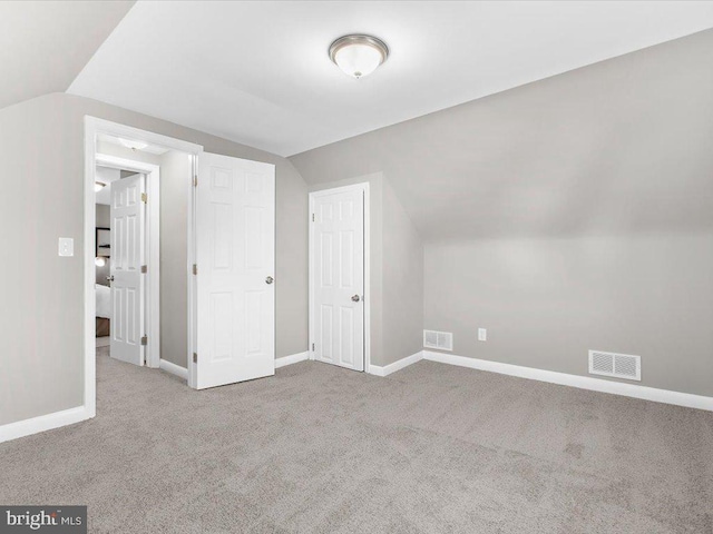 additional living space featuring light carpet and vaulted ceiling