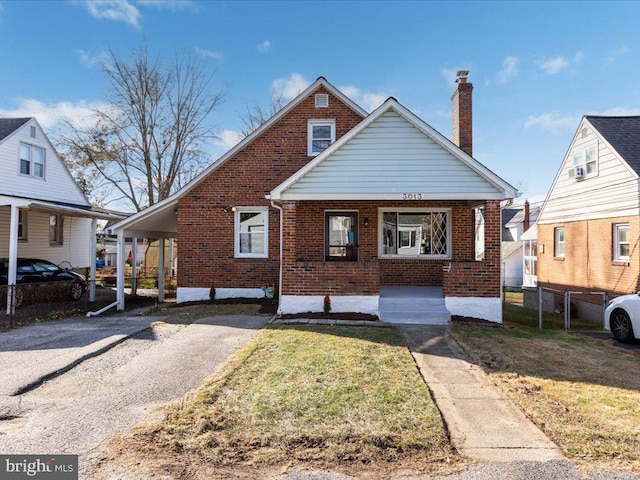 bungalow-style house with a front yard, a carport, and covered porch