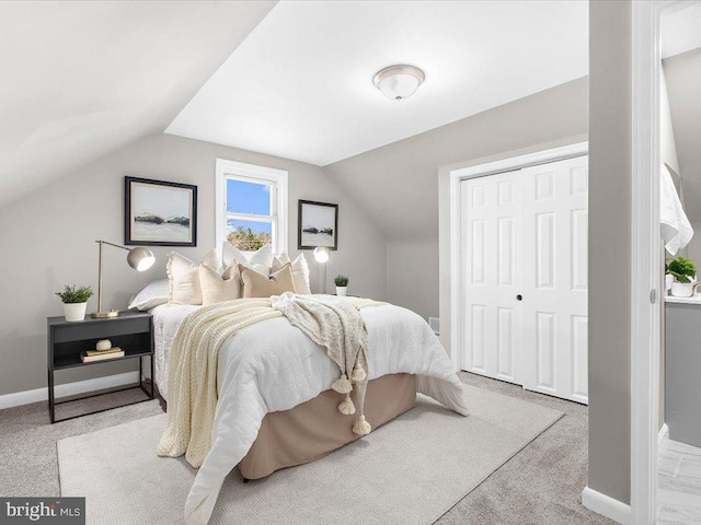 bedroom with light carpet, vaulted ceiling, and a closet