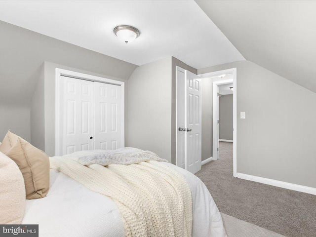 carpeted bedroom featuring vaulted ceiling and a closet