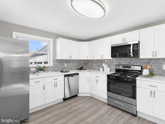 kitchen with sink, white cabinets, light hardwood / wood-style floors, and appliances with stainless steel finishes