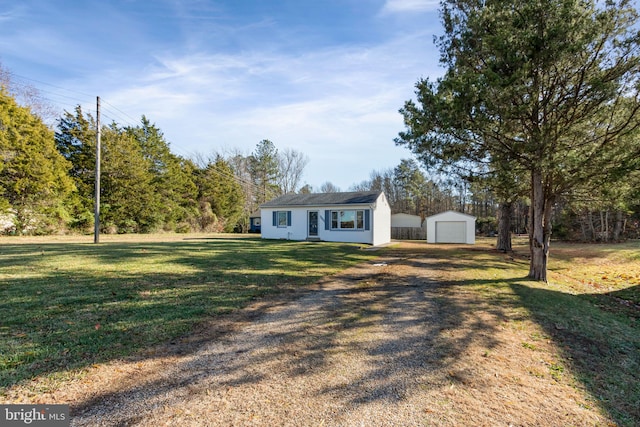 view of front facade featuring a garage, an outbuilding, and a front lawn