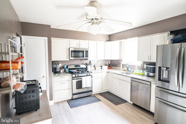 kitchen with light wood-type flooring, white cabinetry, sink, and appliances with stainless steel finishes