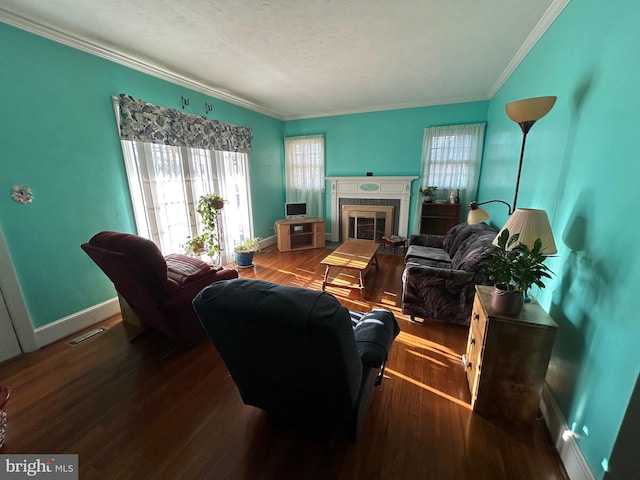 living room featuring a tile fireplace, a textured ceiling, hardwood / wood-style flooring, and ornamental molding