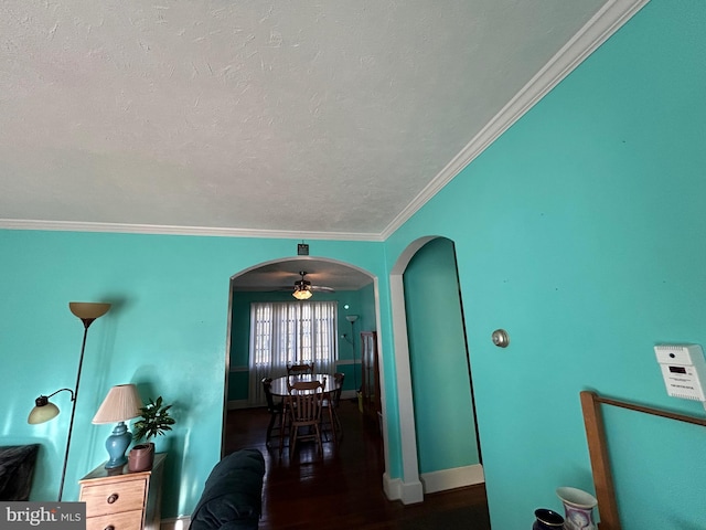 interior space with ceiling fan, dark hardwood / wood-style flooring, a textured ceiling, and ornamental molding