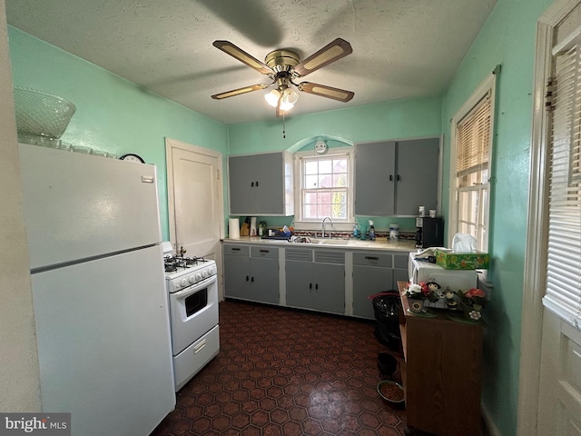 kitchen featuring a textured ceiling, white appliances, ceiling fan, and sink