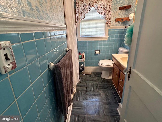 bathroom with tile patterned flooring, vanity, toilet, and tile walls