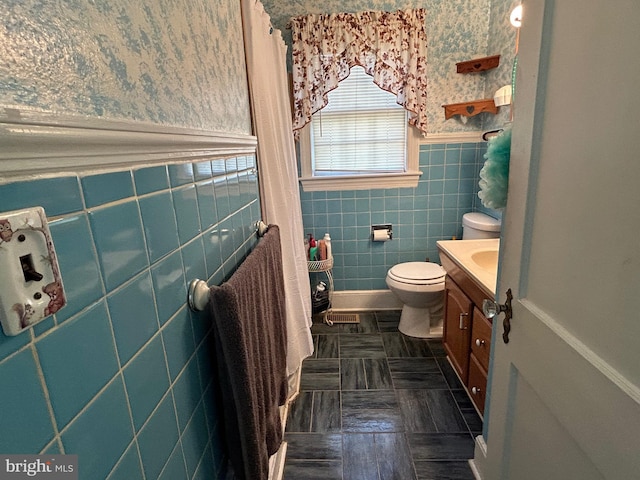 bathroom with tile patterned floors, vanity, toilet, and tile walls